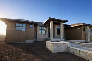 Rear view of property featuring stone siding and a patio