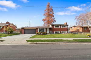 View of front of house with brick siding, a chimney, driveway, and a garage