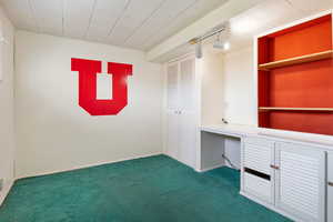 Unfurnished office with dark colored carpet, rail lighting, built in features, and built in study area