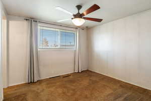 Carpeted spare room featuring a ceiling fan