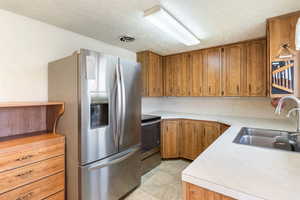 Kitchen featuring brown cabinets, stainless steel appliances, light countertops, and a textured ceiling