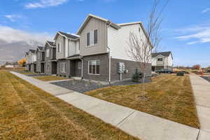 View of side of home with a yard, a residential view, brick siding, and board and batten siding