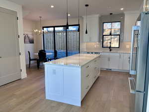Kitchen featuring white cabinetry, freestanding refrigerator, backsplash, and recessed lighting