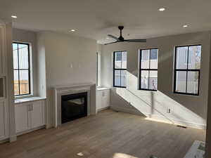 Unfurnished living room with light wood-style floors, recessed lighting, a glass covered fireplace, and a ceiling fan