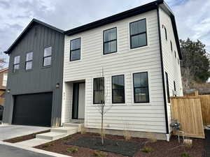 View of front facade featuring board and batten siding, a garage, and driveway