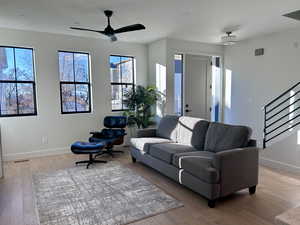 Living area with stairs, a ceiling fan, light wood-style floors, and recessed lighting