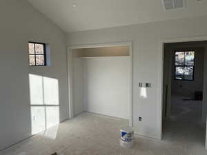 Unfurnished bedroom featuring multiple windows, a closet, and lofted ceiling