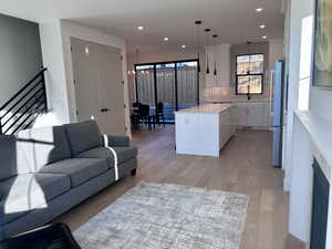 Living area with light wood-type flooring, a chandelier, and recessed lighting