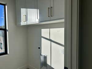 Laundry room with healthy amount of natural light, hookup for an electric dryer, and cabinet space