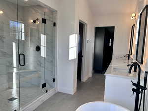 Primary Ensuite Bathroom featuring a marble finish shower, double vanity, a freestanding tub, and light tile patterned floors