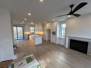 Kitchen with a kitchen island, white cabinets, open floor plan, light wood-type flooring, and recessed lighting