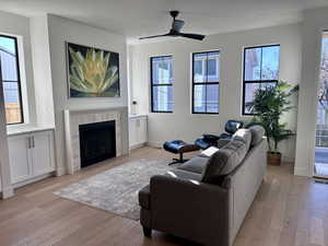Living area with a tile fireplace, light wood-type flooring, ceiling fan, and recessed lighting