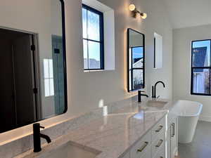 Primary Ensuite featuring double vanity, a freestanding bath, healthy amount of natural light, and light tile patterned floors