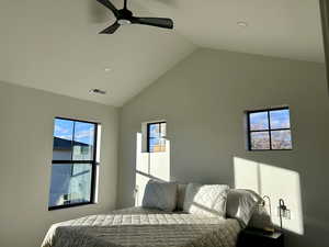 Bedroom with lofted ceiling, multiple windows, and a ceiling fan