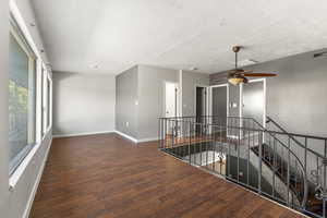 Empty room featuring ceiling fan and dark wood-style flooring