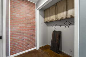 Mudroom featuring brick wall and concrete floors