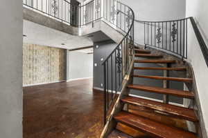 Stairway featuring a high ceiling and finished concrete flooring