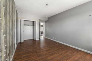 Unfurnished bedroom with dark wood-type flooring, a closet, and a textured ceiling