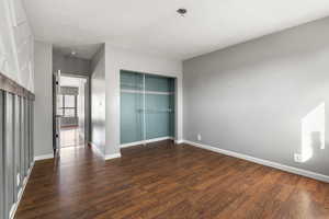 Unfurnished bedroom featuring a closet and dark wood finished floors