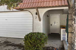 Doorway to property featuring a tile roof and stucco siding
