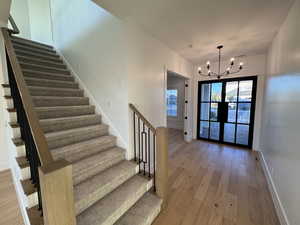 Stairway with wood-type flooring and a chandelier