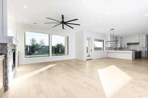 Unfurnished living room with a fireplace, ceiling fan, light wood-style floors, and recessed lighting