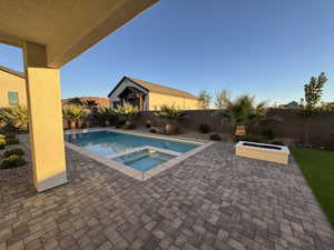 View of pool with a patio, a fenced backyard, and a pool with connected hot tub