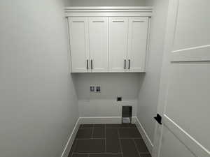 Laundry area with electric dryer hookup, cabinet space, washer hookup, and dark tile patterned flooring