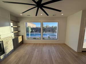 Unfurnished living room with light wood-style flooring, a ceiling fan, recessed lighting, and a fireplace