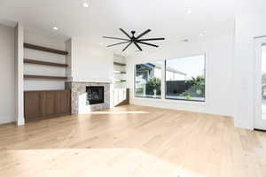Unfurnished living room with a glass covered fireplace, recessed lighting, light wood-type flooring, and a ceiling fan