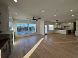 Unfurnished living room with recessed lighting, a fireplace, light wood finished floors, and a ceiling fan