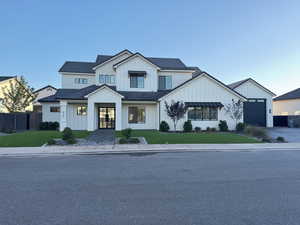 Modern farmhouse style home featuring board and batten siding and a front lawn