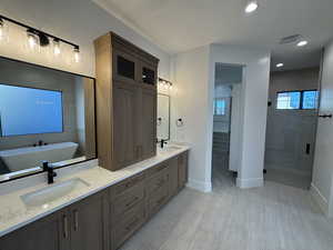 Bathroom with double vanity, recessed lighting, and a stall shower