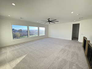 Spare room with light colored carpet, a ceiling fan, recessed lighting, and wood walls