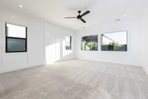 Unfurnished room with light carpet, a ceiling fan, a decorative wall, and recessed lighting