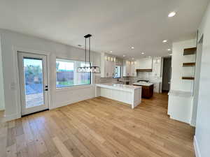 Kitchen featuring glass insert cabinets, white cabinetry, a peninsula, decorative backsplash, and recessed lighting