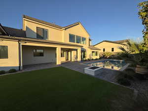 Rear view of property with a patio, stucco siding, an outdoor pool, and a lawn