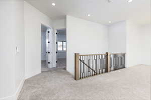 Empty room with light carpet and recessed lighting