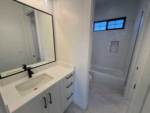Full bath featuring vanity, shower / bath combination, and light marble finish flooring