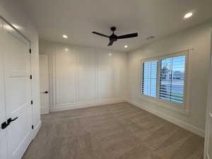 Unfurnished room with a decorative wall, light carpet, a ceiling fan, and recessed lighting