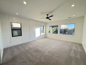 Spare room featuring a decorative wall, plenty of natural light, light colored carpet, ceiling fan, and recessed lighting
