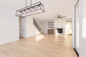 Unfurnished living room with light wood-style flooring, a fireplace, recessed lighting, a ceiling fan, and stairway
