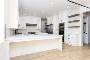 Kitchen featuring open shelves, white cabinets, backsplash, appliances with stainless steel finishes, and recessed lighting