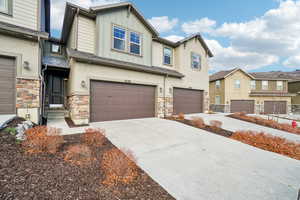 Craftsman house featuring stone siding, board and batten siding, driveway, a garage, and stucco siding