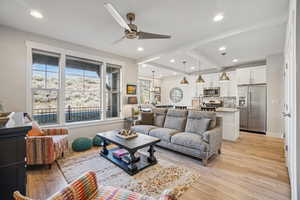 Living room with light wood finished floors, beamed ceiling, a ceiling fan, and recessed lighting