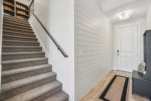 Entrance foyer featuring light wood-type flooring, shiplap walls, and a stairway
