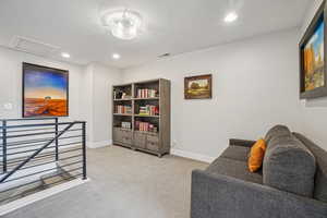 Sitting room with an upstairs landing, recessed lighting, light colored carpet, and attic access