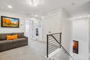 Living area with an upstairs landing, recessed lighting, and carpet flooring