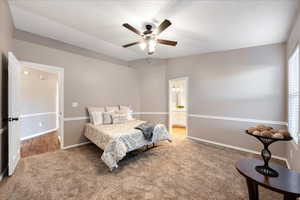 Bedroom featuring ceiling fan, carpet flooring, and ensuite bath