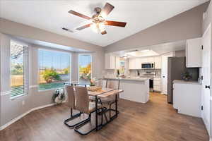 Dining area featuring a ceiling fan, views, light wood finished floors, and lofted ceiling